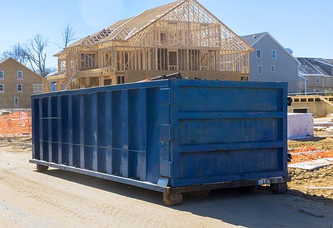 a pile of construction debris overflowing from a residential dumpster near a job site